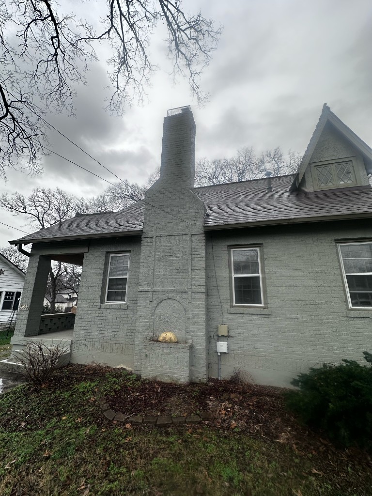 Painted gray brick chimney before masonry rebuild